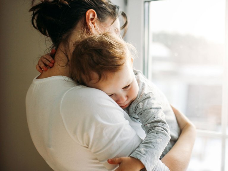 Eine Mutter hält ihr Kind in den Armen, welches sich ankuschelt