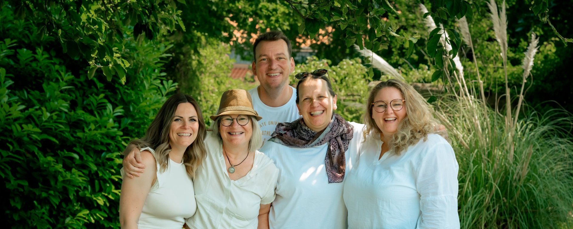 Ein Gruppenfoto von vier lachenden Frauen und einem Mann im Garten.
